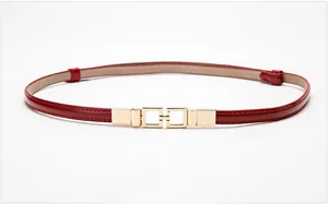 Detail of red patent leather thin belt with elegant gold square interlocking buckle