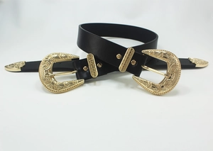 Detail view of vintage engraved gold buckles on a black leather belt in Western style