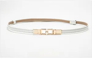 Detailed view of the white patent leather belt with minimalist gold geometric buckle