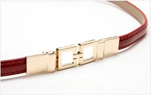 Detail of red patent leather belt with stylish interlocking square gold metal buckle