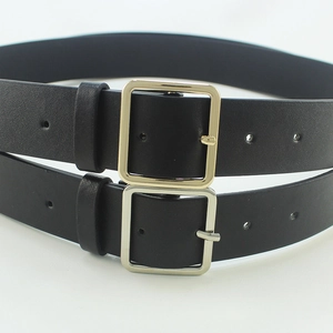 Minimalist black leather belts with square gold and silver metal buckles in a stack