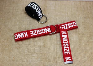 Detalle de cinturones de lona con estampado KINGSIZE blanco y hebillas metálicas de doble anilla