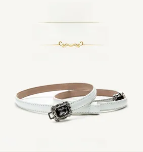 Detail view of white patent leather skinny belt with adjustable buckle and black gemstone