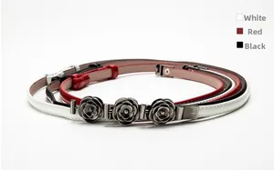 Detailed view of skinny belts with triple camellia metal buckles in white, red and black
