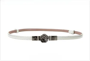 Close-up of white minimalist leather belt featuring a gunmetal camellia flower buckle