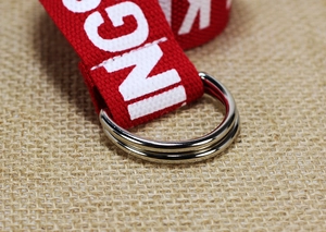 Detalle de cinturón de lona de nailon rojo con letras blancas y hebilla de doble anilla D