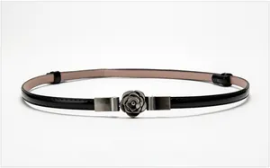Detail view of glossy black patent leather skinny belt with elegant metal camellia buckle