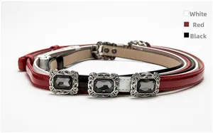 Detailed view of women's skinny belts in black, red, and white with elegant gemstone buckles