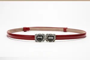 Close-up of a slim red patent leather belt with a vintage crystal-embedded buckle