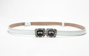 Detail of white thin belt with vintage silver buckle and grey gemstone accents