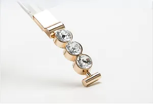 Detailed macro view of a gold buckle belt with three inlaid crystals on white leather