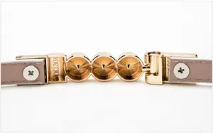 Macro view of gold metal buckle with engraved model DK1304 on pink leather belt strap
