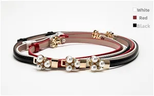 Dettaglio di cinture sottili con fibbie floreali in perle e strass dorati in bianco, rosso e nero