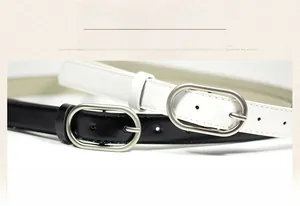 Close-up of slim black and white leather belts with oval silver pin buckles for women