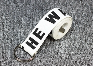 Detail of white nylon canvas belt featuring double D-ring metal buckle and HE WA text