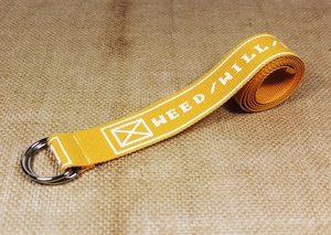 Detailed macro view of yellow nylon canvas belt with double D-ring and industrial text print