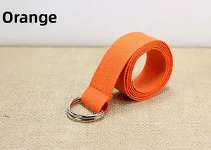 Détail d'une ceinture orange en nylon avec boucle double D argentée sur fond en lin