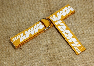 Macro detail of yellow canvas belt with silver D-ring buckle and printed MMY pattern