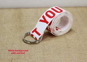 Détail de la ceinture en toile avec texte rouge sur sangle blanche et boucles en D