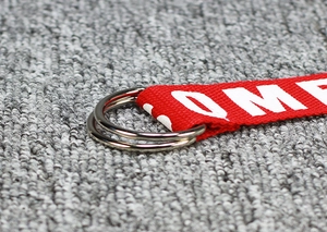 Detail of red nylon woven keychain with white lettering and double silver metal rings