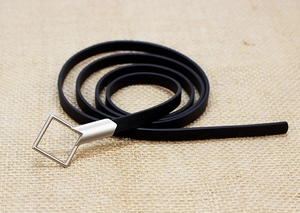 Detailed macro of a black leather belt with a silver square buckle on a linen background