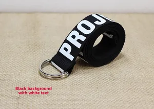 Détail d'une ceinture en toile noire avec texte PROJECT blanc et boucle double D en argent