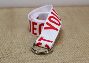 Détail de la ceinture en toile de nylon blanc avec lettres rouges et boucle double D argentée