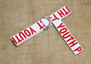 Détail de ceinture en toile blanche avec texte rouge et boucles métalliques à double anneau D
