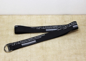 Détail d'une ceinture en nylon noir avec imprimé blanc et boucles doubles en D argentées