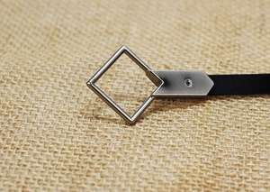 Macro shot of black leather belt with silver square buckle and sparkling crystal inlay