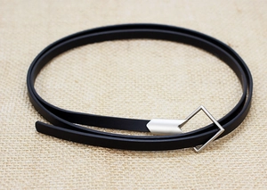 Close-up of slim black leather belt with silver geometric diamond buckle on linen