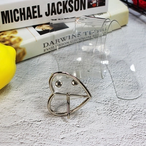 Dettaglio di una cintura in PVC trasparente con una grande fibbia in metallo a forma di cuore