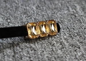 Close-up of black skinny belt with champagne rectangular gemstones in gold metal settings