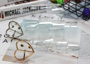 Dettaglio di cinture trasparenti in PVC con fibbie metalliche a cuore color oro e argento