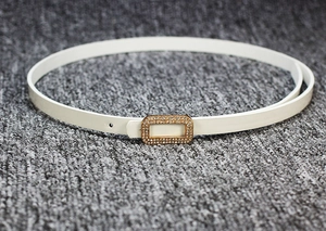 Detail of slim white patent leather belt with a gold rectangular rhinestone-encrusted buckle