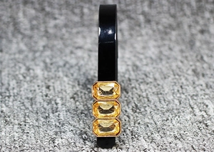 Detail view of glossy black headband with three vertically set yellow rectangular crystals