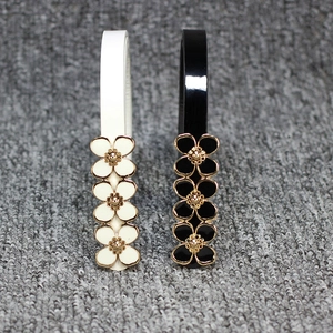 Détail de ceintures en cuir verni blanc et noir avec boucles à fleurs en émail doré élégantes