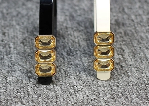 Close-up of headband detail featuring three golden rectangular gems in metal frames