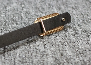 Macro detail of dark brown matte leather belt with vintage golden rectangular buckle