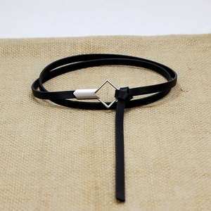 Minimalist black leather belt for women with modern silver geometric buckle on burlap