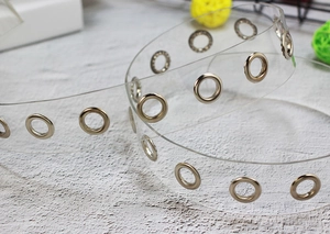 Detailed macro view of flexible transparent PVC belt with polished silver metal eyelets