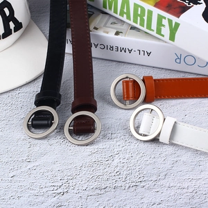 Flat lay of four minimalist thin belts in black, brown, tan, and white with silver buckles