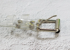 Detail of transparent PVC belt with silver square buckle and metal rivet fasteners