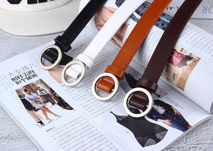 Detailed macro of four slim faux leather belts with polished silver round buckles