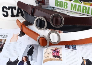 Flat lay of minimalist faux leather belts in four colors with round silver metal buckles