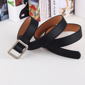 Detail of thin black faux leather belt with silver square buckle on white surface