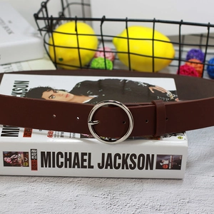 Détail de la ceinture en cuir marron rouge foncé avec une boucle ronde en métal argenté