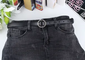 Nahaufnahme eines schmalen schwarzen Ledergürtels mit silberner Rundschnalle auf Denim