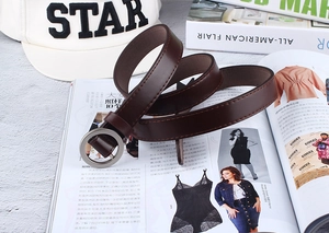 Detail of dark brown faux leather skinny belt with round silver buckle on magazines