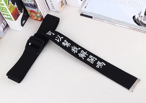 Détail de la ceinture en toile noire avec boucle double anneau et texte blanc imprimé